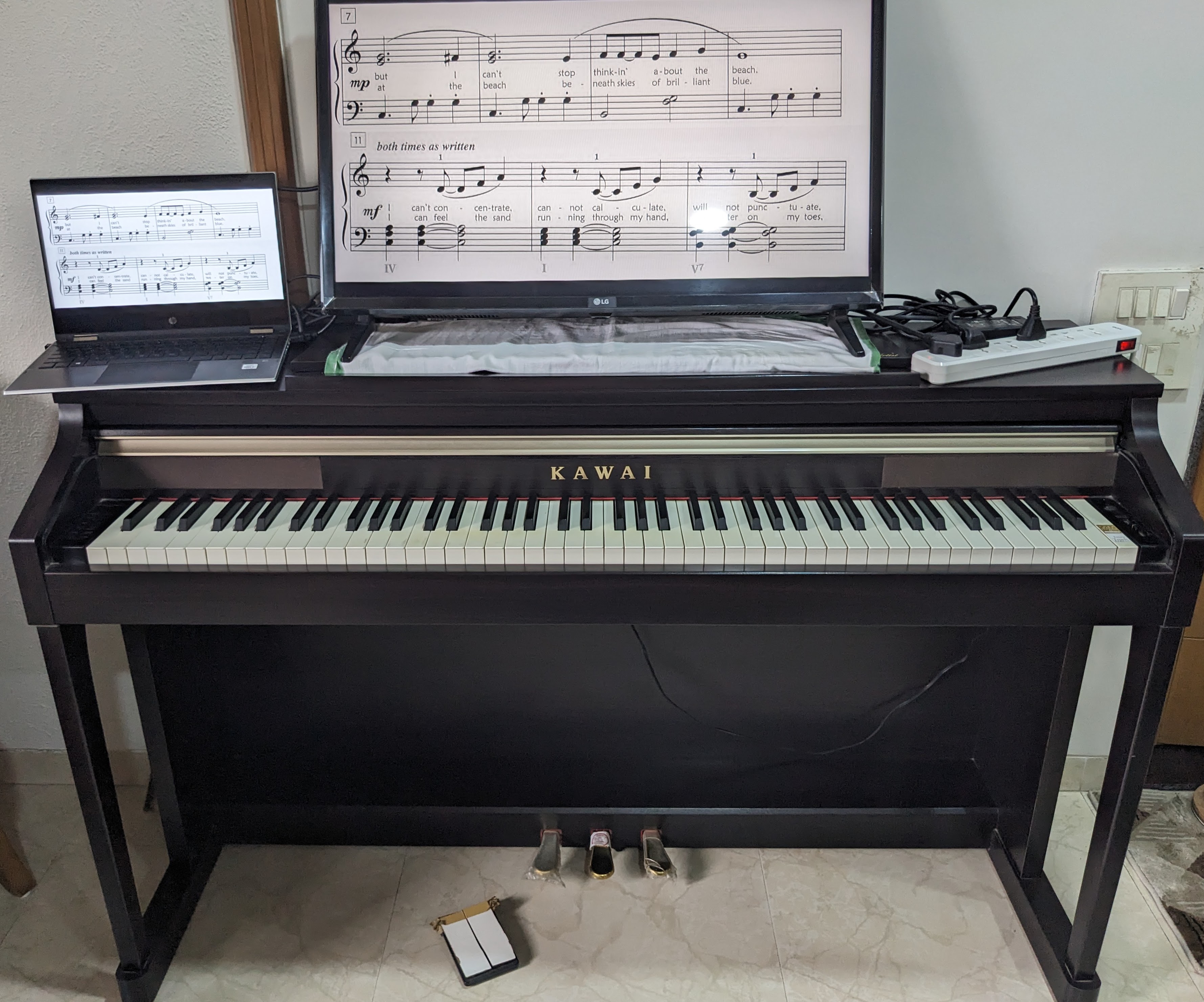 Setup showing laptop connected to large screen with foot pedals for page turning